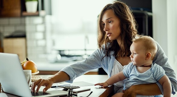 Eine Frau mit einem Baby arbeitet am Computer