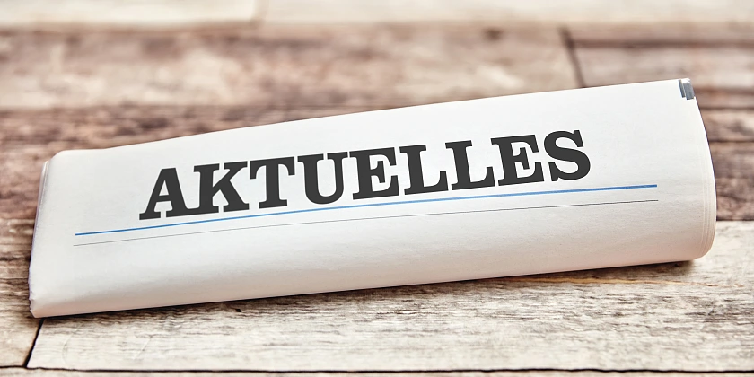 eine gerollte Zeitung lieg auf einem Brett