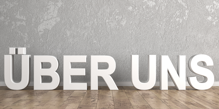Buchstaben stehen vor einer Wand und bilden die Worte über uns