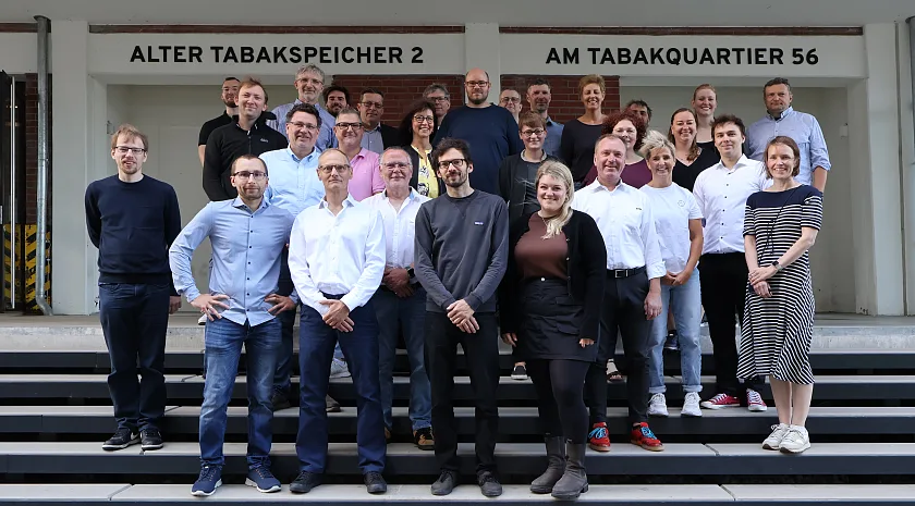 30 Personen aus der Abteilung 4 stehen auf der Treppe im Eingang zum Alten Tabakspeicher II