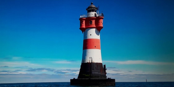 Leuchtturm roter Sand vor blauem Himmel