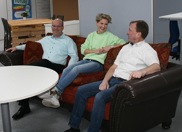 Zwei Männer und eine Frau sitzen auf einem Sofa