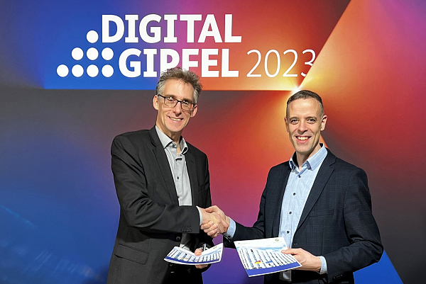 Dr. Hagen und Dr. Richte schütteln sich die Hände vor einer mit Digital-Gipfel beschriebenen Wand