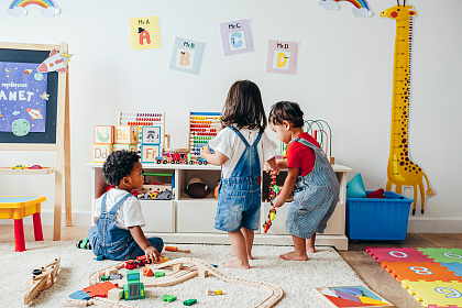 Drei Kleinkinder spielen gemeinsam in einem Spielzimmer. 